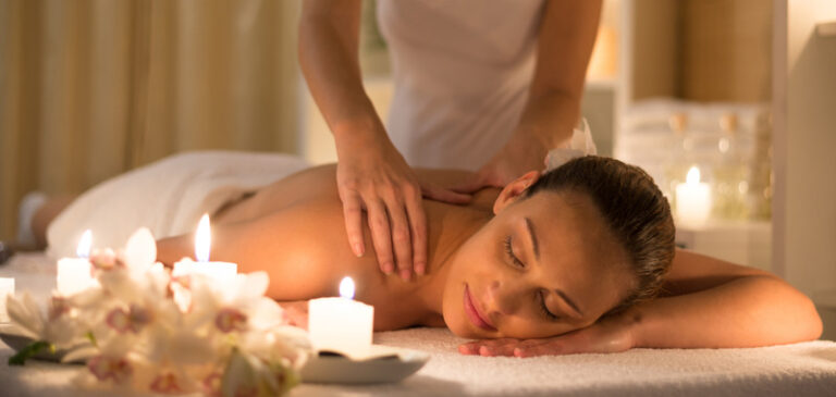 Woman receiving shoulder massage at spa and beauty salon / candle light